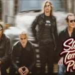 Foto promocional da banda Stone Temple Pilots com os quatro integrantes vestindo roupas escuras, posando em frente a um caminhão desfocado ao fundo. O logotipo da banda aparece no canto inferior direito.