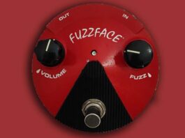 Pedal fuzz face vintage sobre fundo escuro com guitarra elétrica ao fundo mostrando conexões e controles.