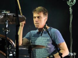 Matt Cameron tocando bateria em show do Pearl Jam, concentrado durante performance ao vivo com iluminação de palco destacando o baterista em ação.